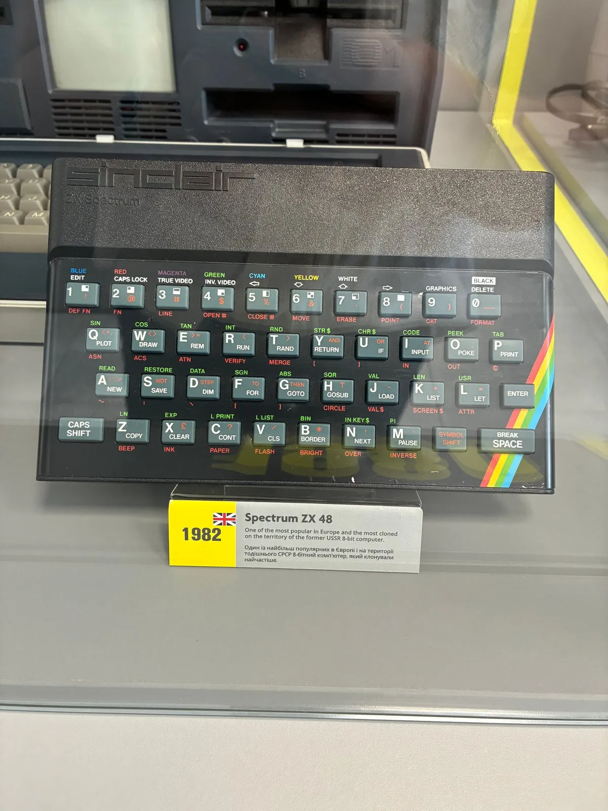 ZX Spectrum 48K у вітрині музею на підставці: чорний корпус із гумовою клавіатурою та райдужною смугою, поряд музейна табличка «1982»
