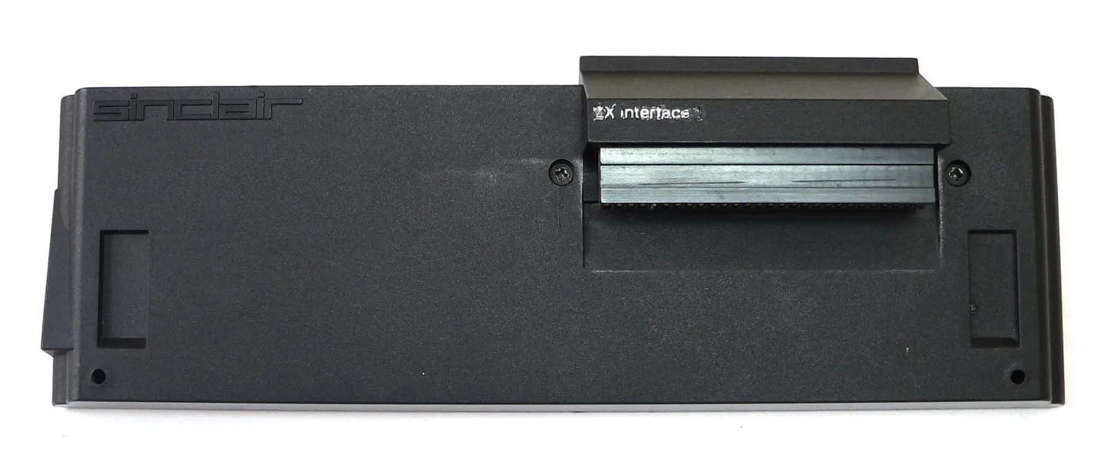 Sinclair ZX Interface 1 — чорний клиноподібний модуль із логотипом «sinclair» і написом «ZX interface 1», видно край-конектор