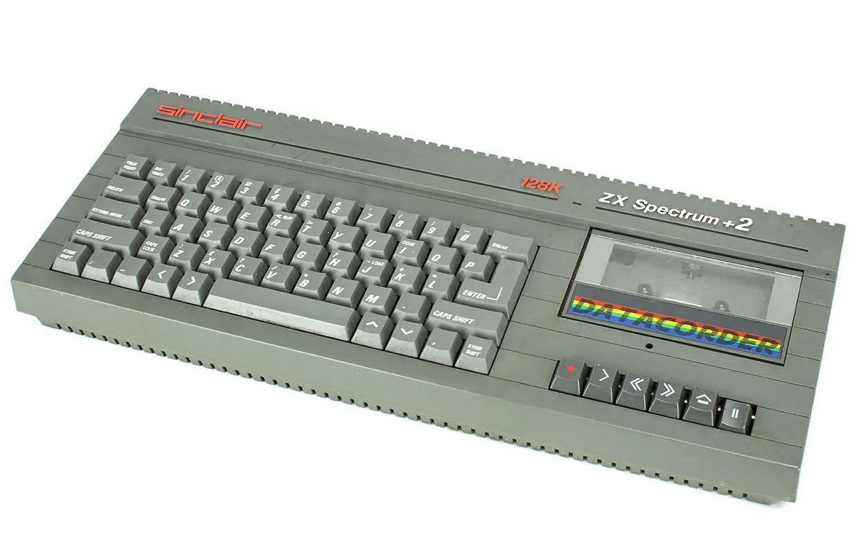 ZX Spectrum +2 — темно-сірий корпус із вбудованим касетником Datacorder, англійська клавіатура та написи «sinclair», «128K», «ZX Spectrum +2»